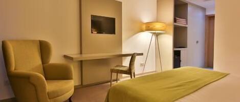 Une chambre d’hôtel avec un lit, un bureau, une chaise et une lampe.