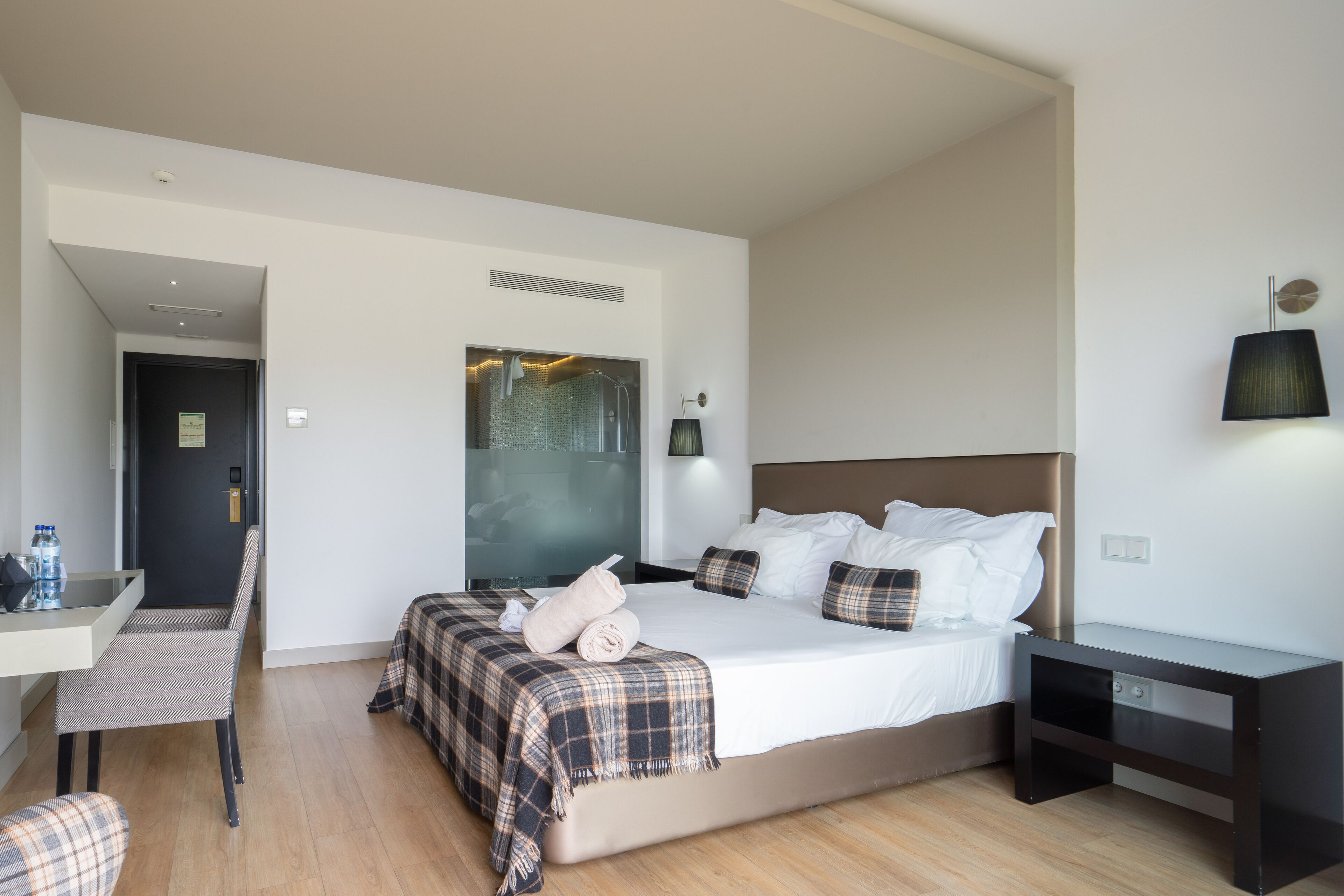 Una habitación de hotel moderna con una cama grande, un escritorio y una silla.
