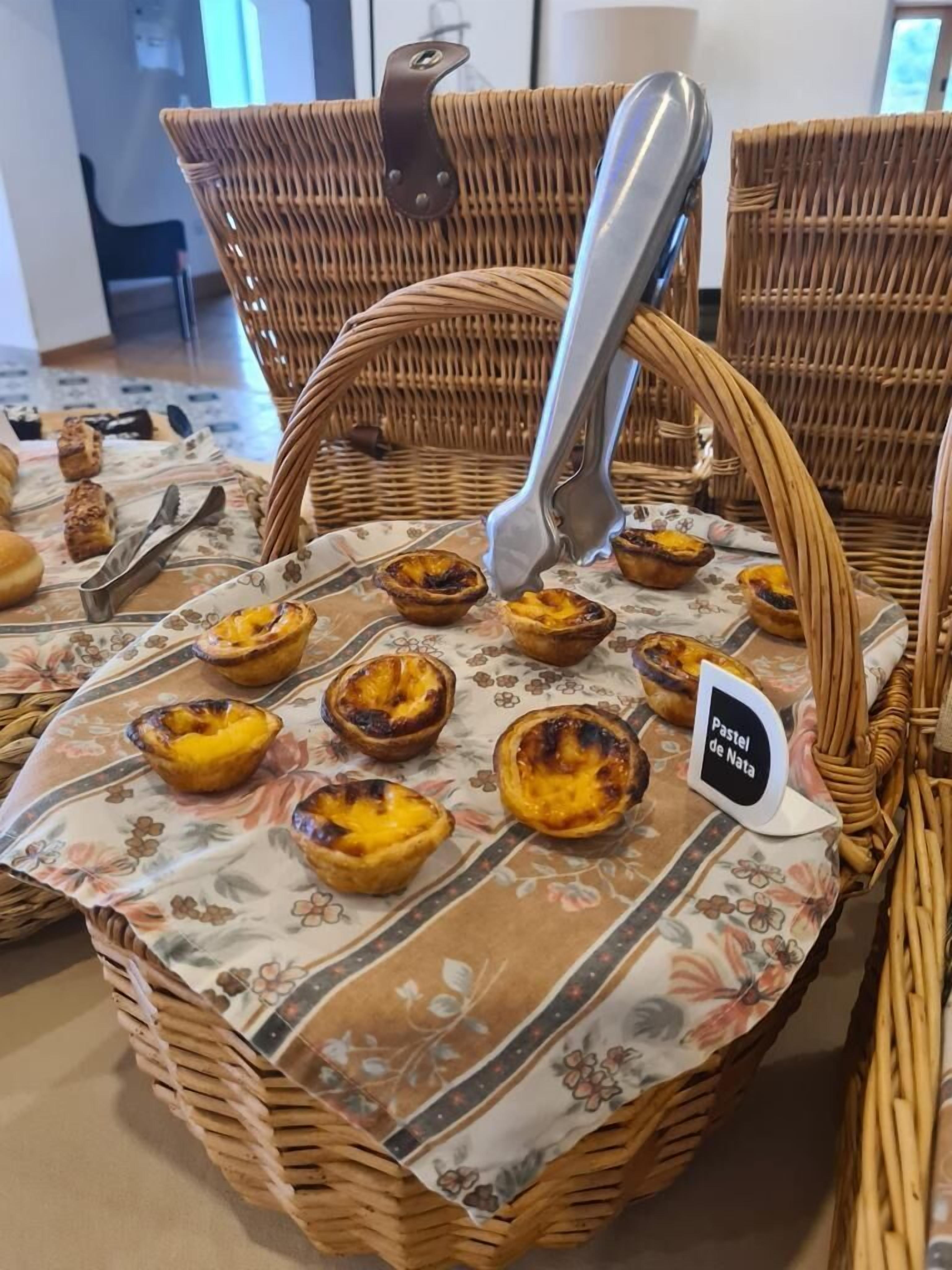 Una cesta de mimbre llena de pasteles de nata sobre un mantel estampado con flores.