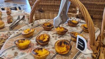Ein Korbwägelchen voller Pastel de Nata auf einer Blumen Tischdecke.