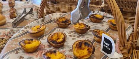 A wicker basket filled with pastel de nata pastries on a floral tablecloth.