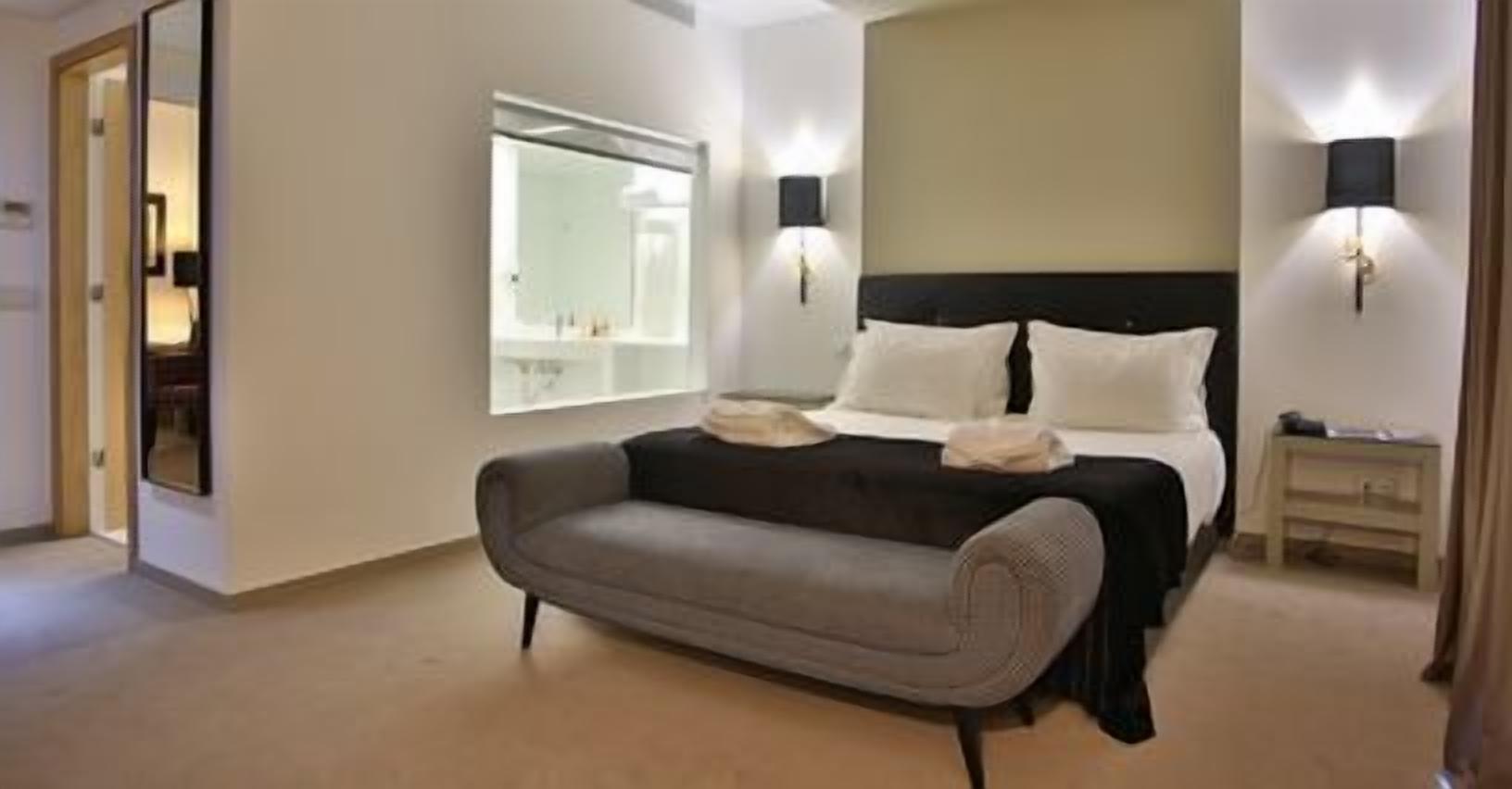 Un dormitorio con cama, sofá, mesita de noche y espejo.