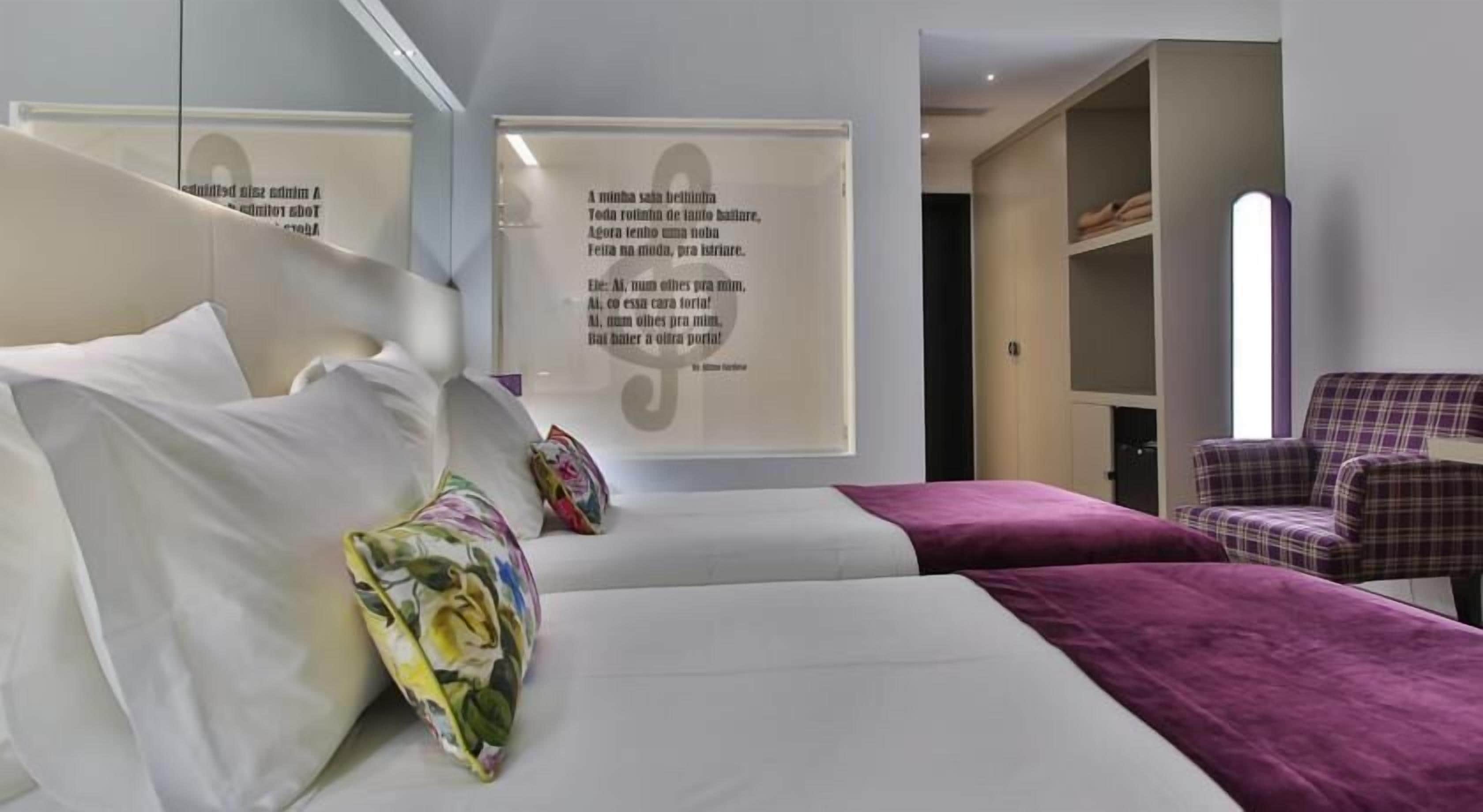 A hotel room with a bed, a chair, and a wardrobe.