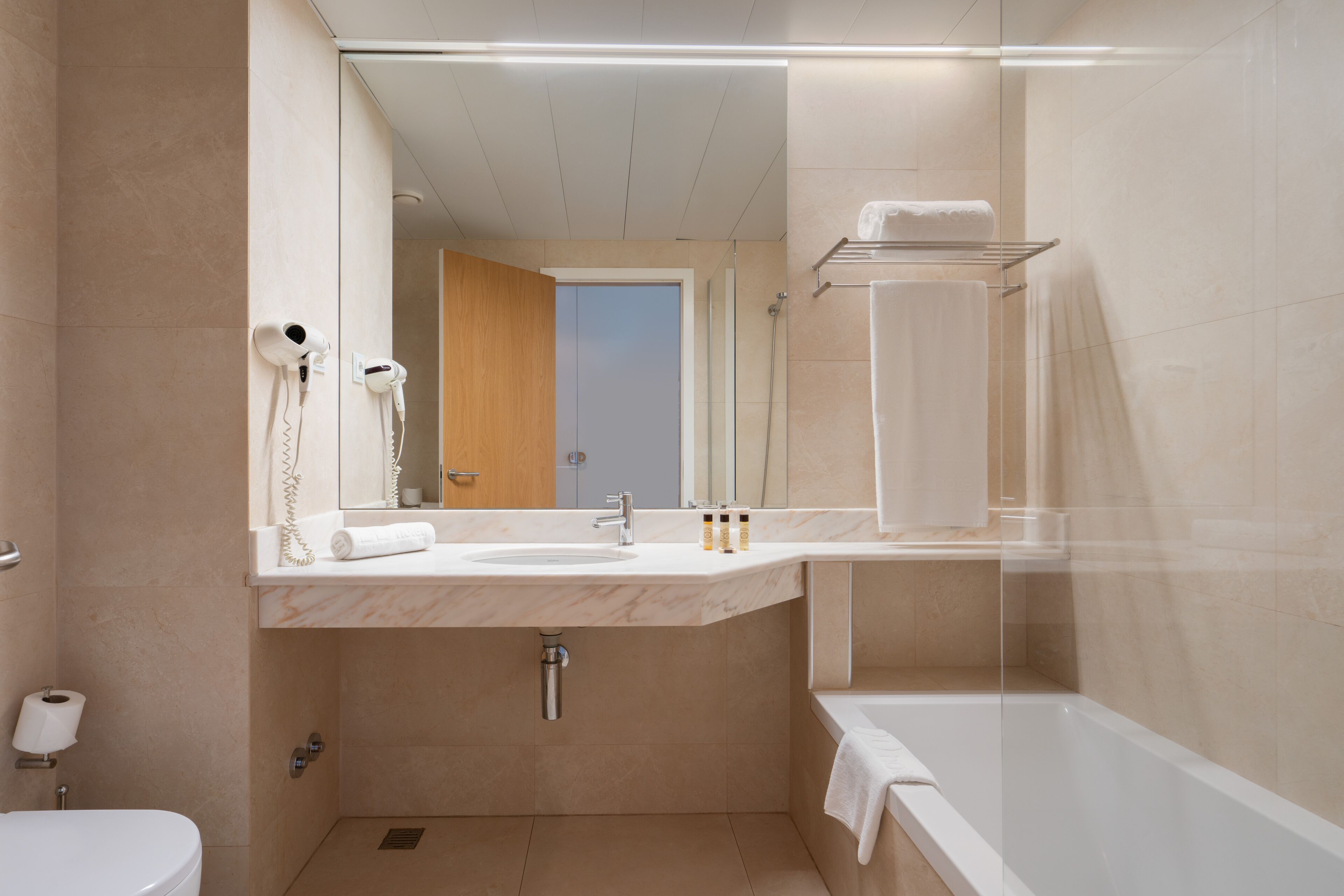 A modern bathroom with a sink, mirror, and bathtub.
