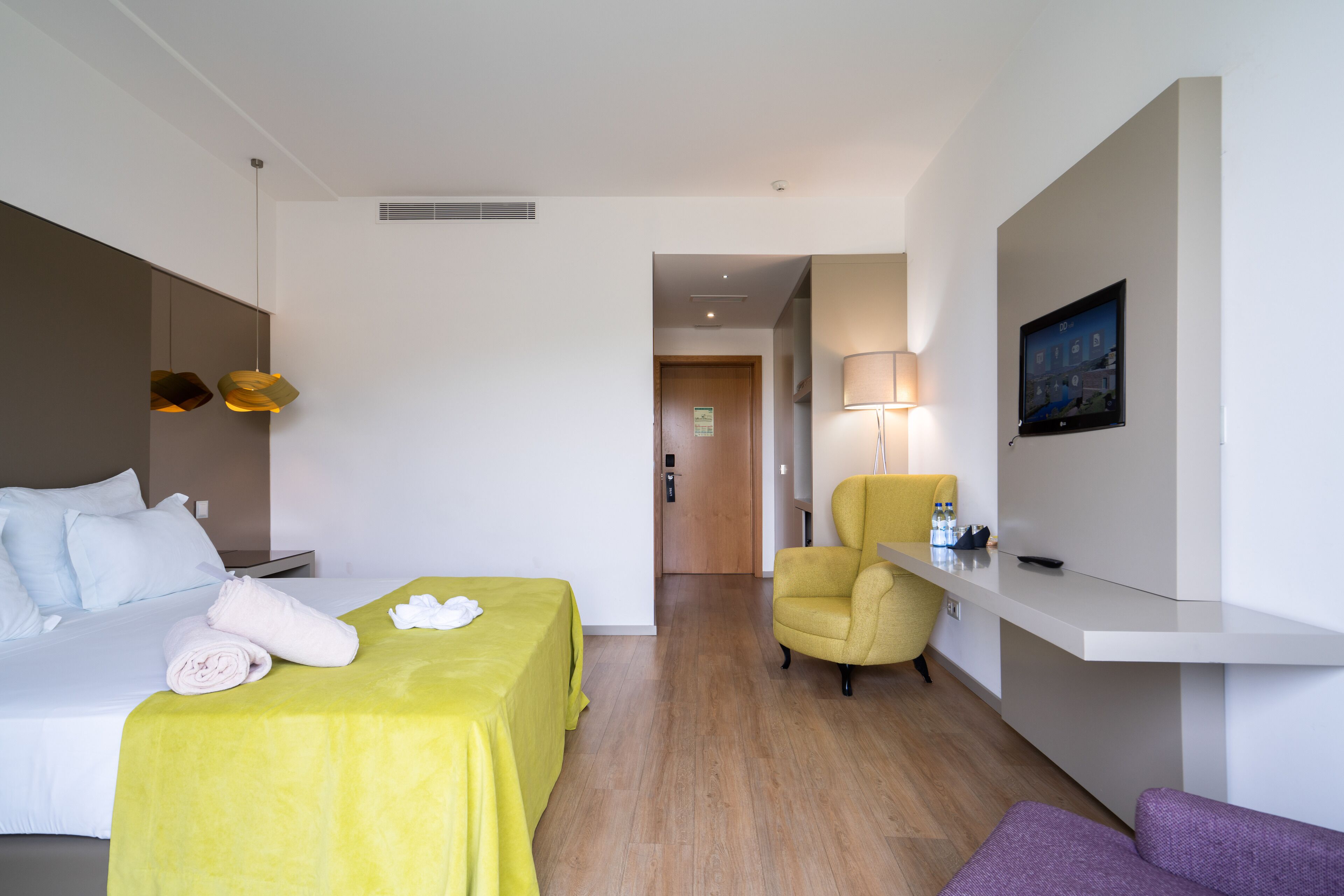 A hotel room with a bed, a desk, a chair, and a sofa.