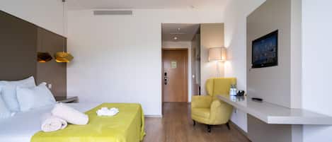 A hotel room with a bed, a desk, a chair, and a sofa.