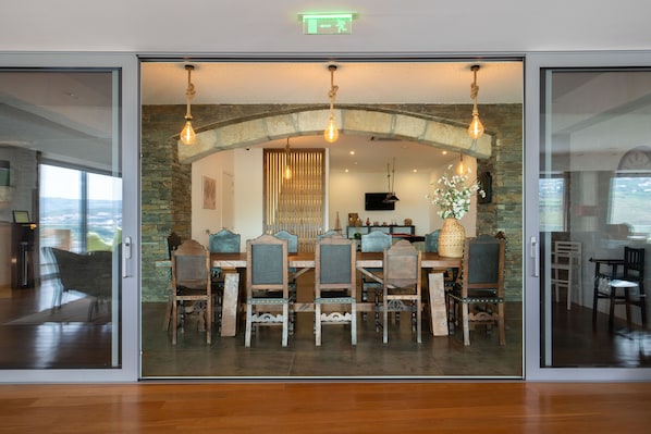 A dining area with a stone arch, wooden chairs, and hanging light fixtures. - Delfim Douro Hotel (Lamego)