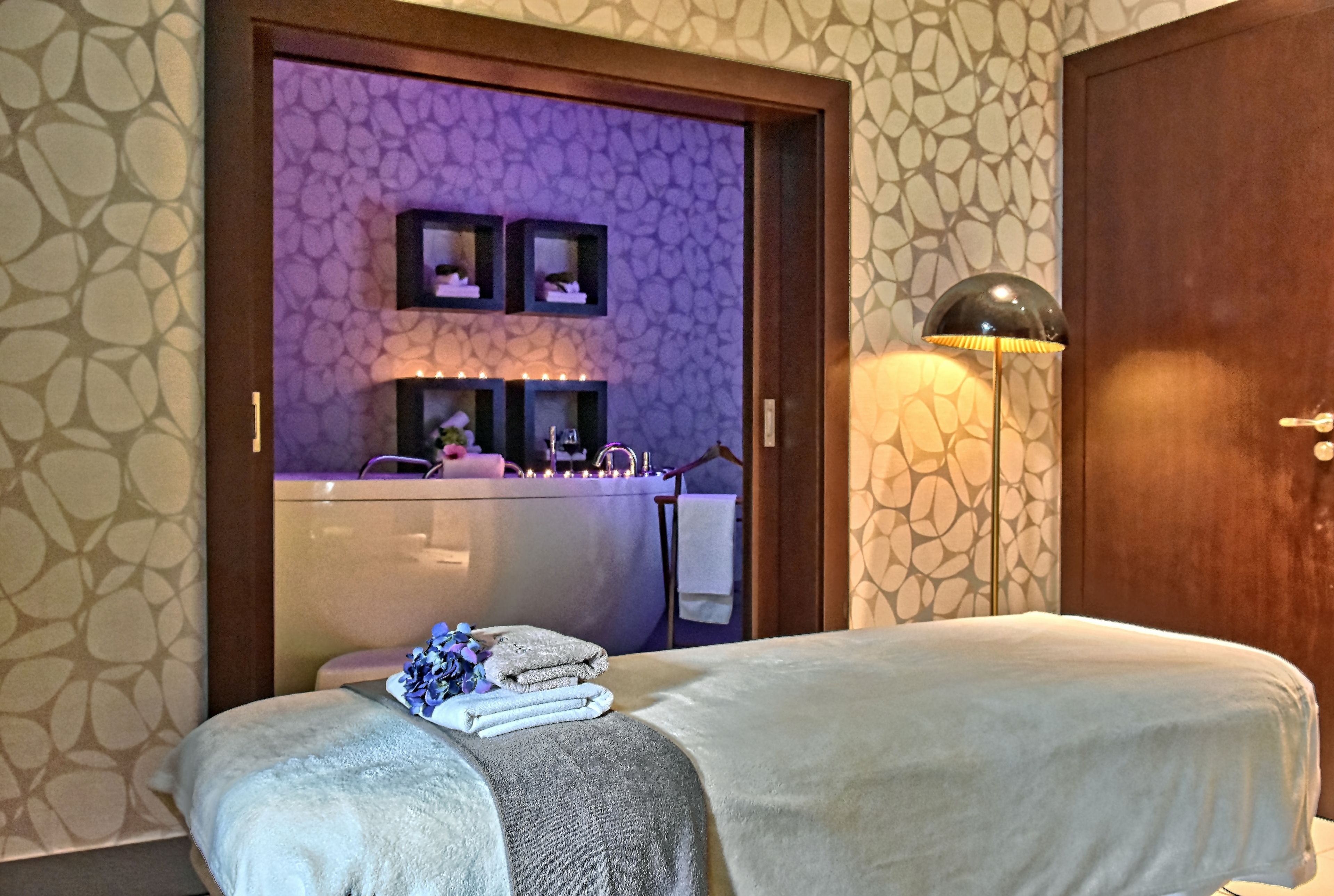 Una habitación de hotel con una cama, una tocador con espejo y una mesita de noche con lámpara.