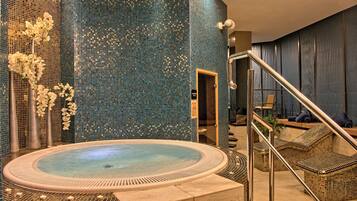 Zona de spa con hidromasaje, asientos y elementos decorativos.