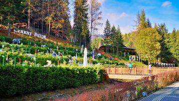 A park with a wooden bridge, a statue, and a sign reading "LEARNY POTOK".