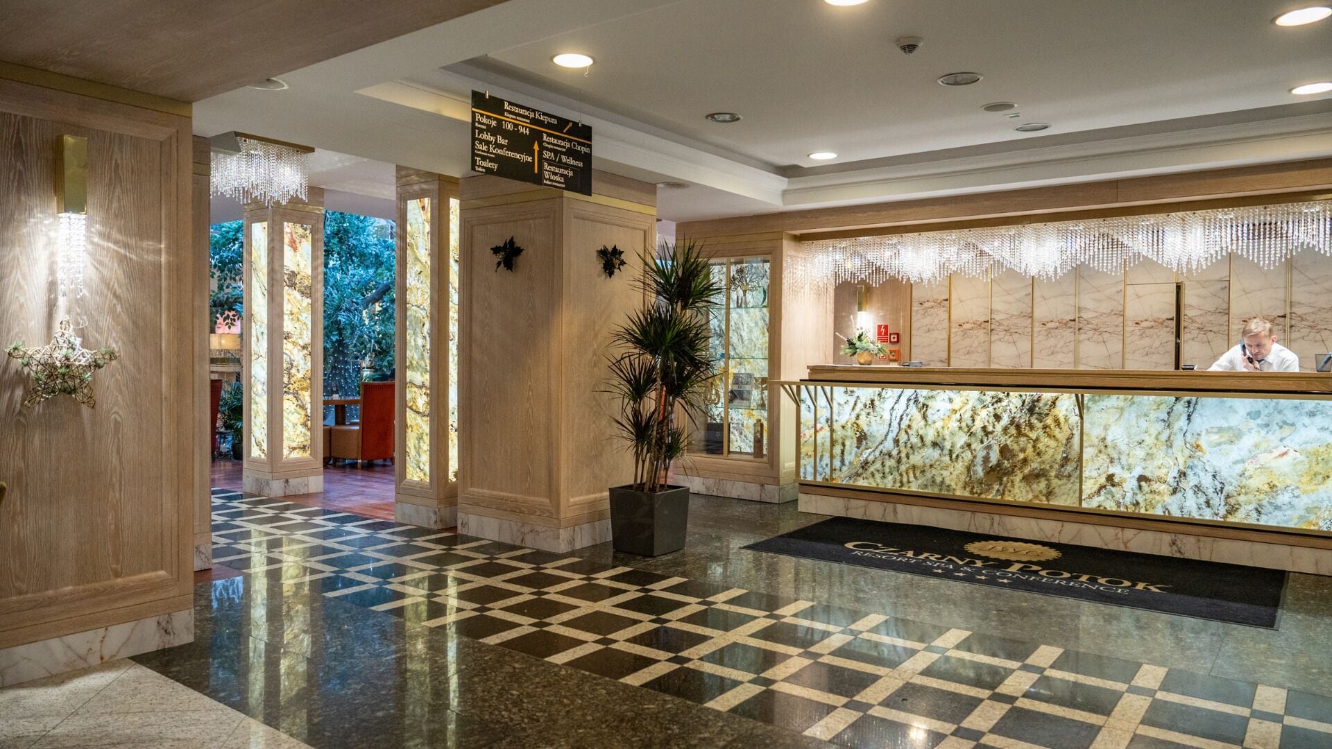 A lobby with a checkered floor, a reception desk, and a sign indicating the lobby area.