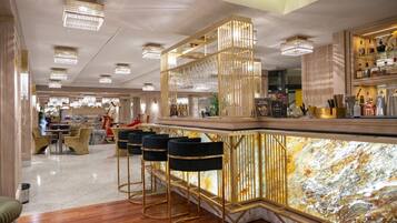 Un elegante bar con encimera de mármol, detalles dorados y modernos taburetes.