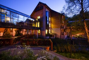 Una casa moderna con un puente de cristal, un ventanal grande y una entrada bien iluminada.
