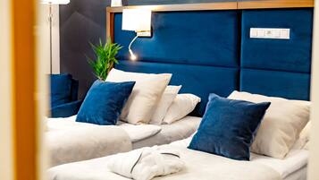 Une chambre d’hôtel avec une tête de lit bleue, deux lits avec une literie blanche et bleue, une table de chevet et une lampe.