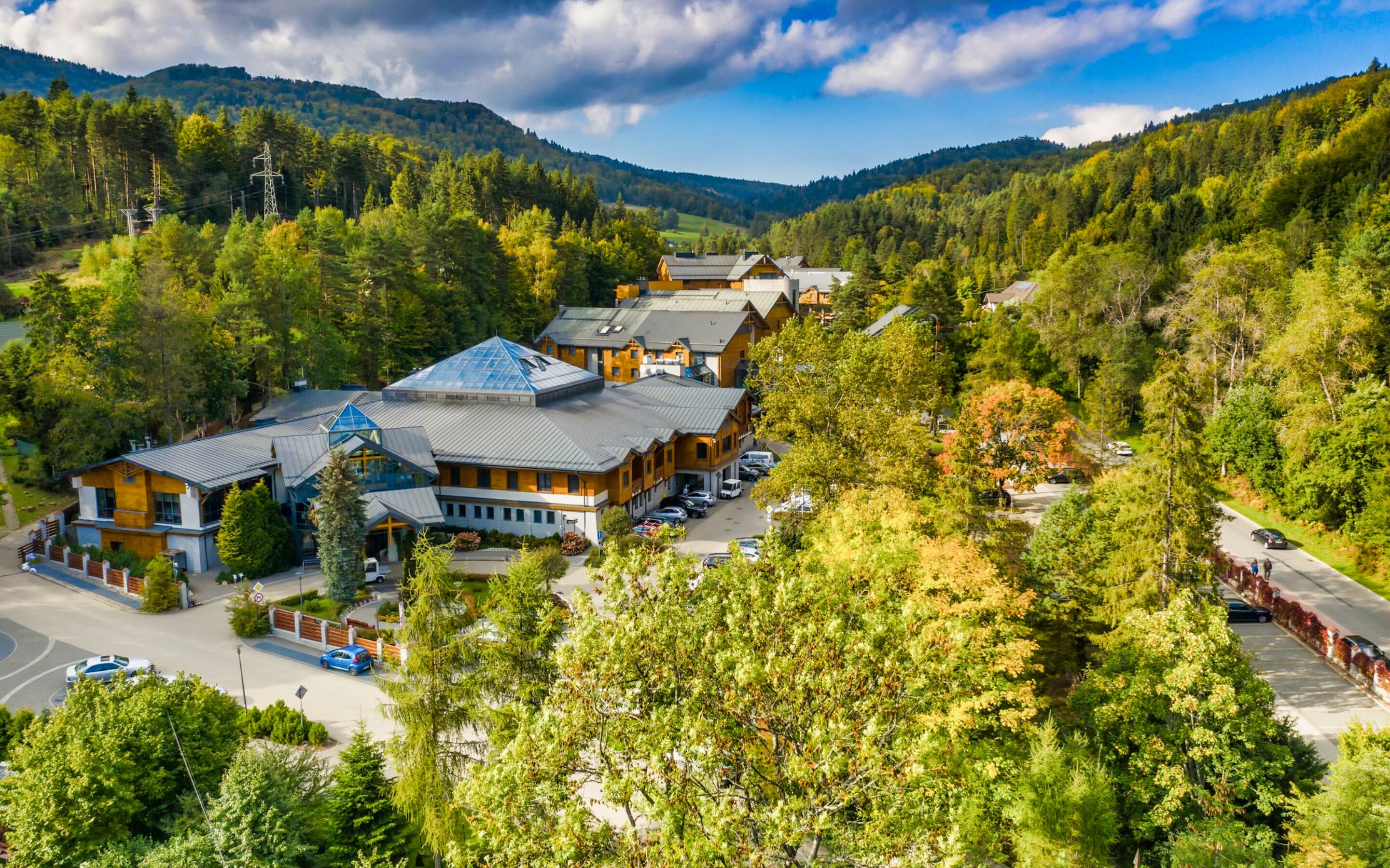 Een lodge met meerdere gebouwen, omgeven door dicht bos en bergen.