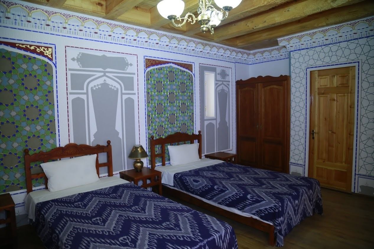 Una habitación con dos camas de madera, una araña y paredes con diseño.