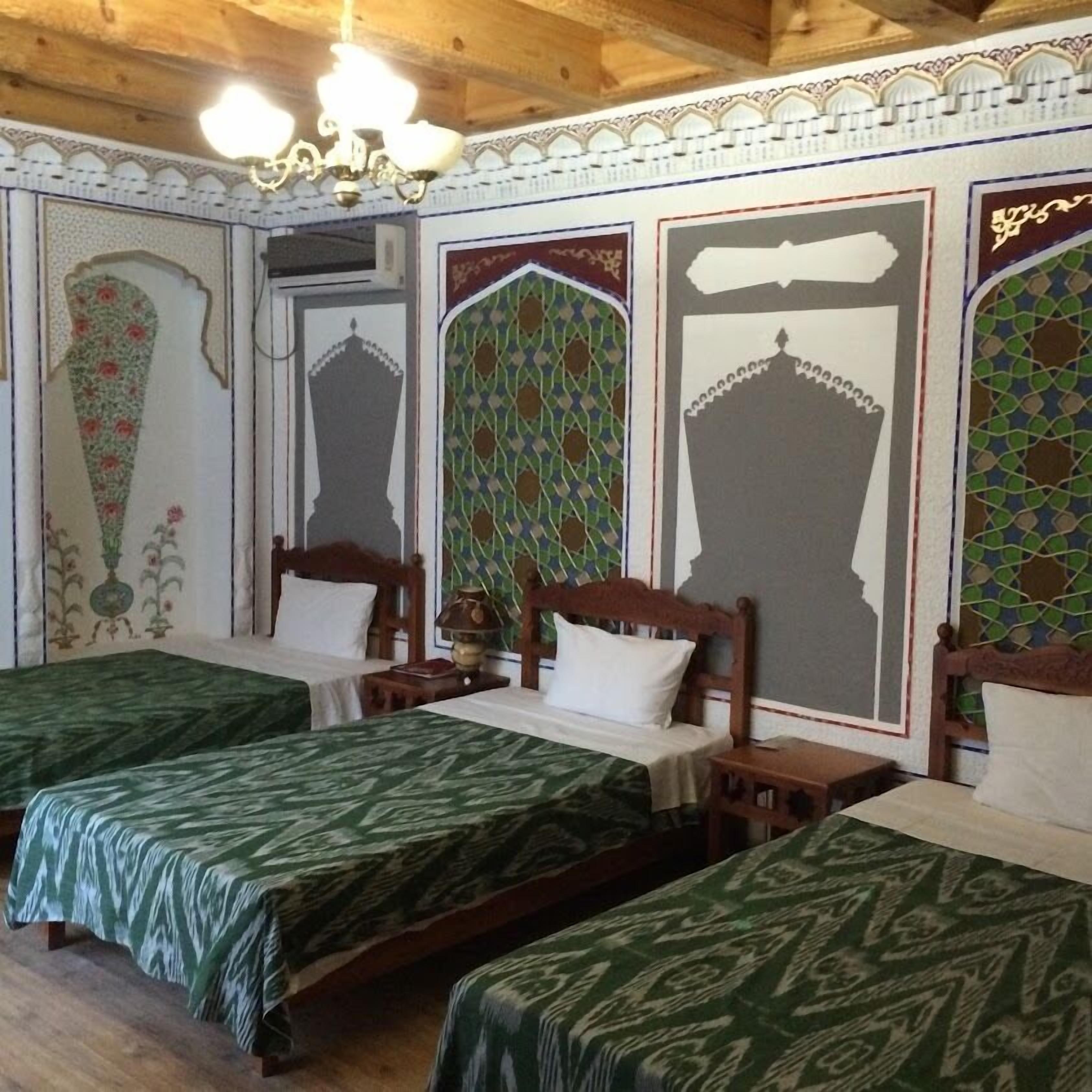 A room with two beds, wooden headboards, and patterned wall decorations.