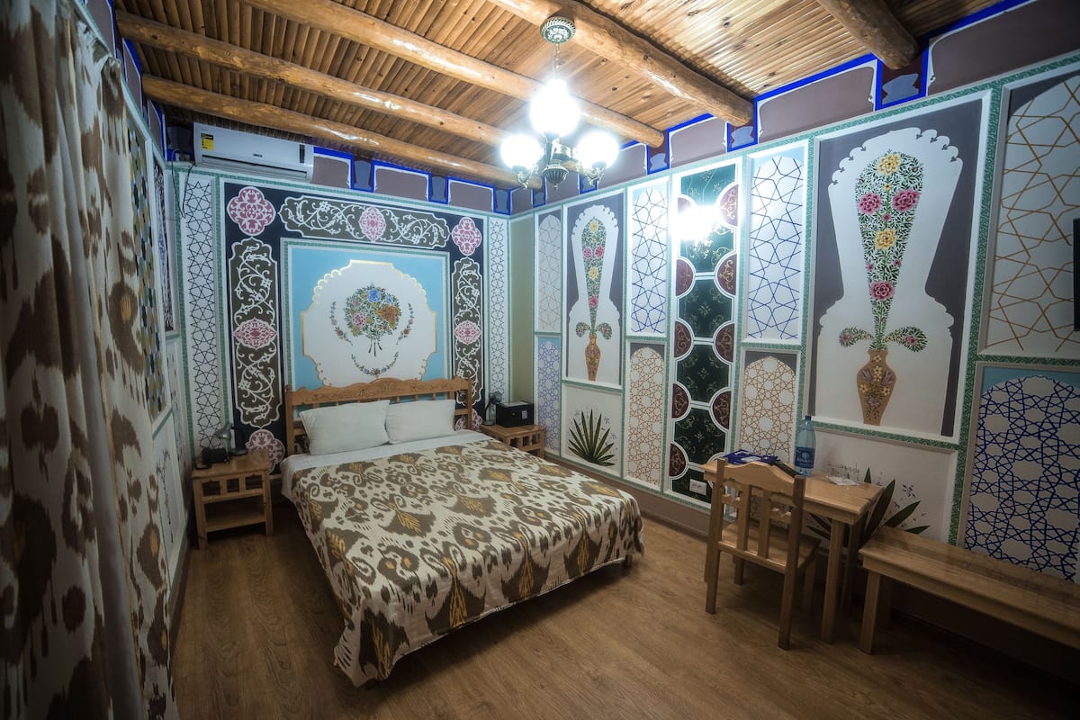 Un dormitorio con una cama y un escritorio de madera, además de un banco.