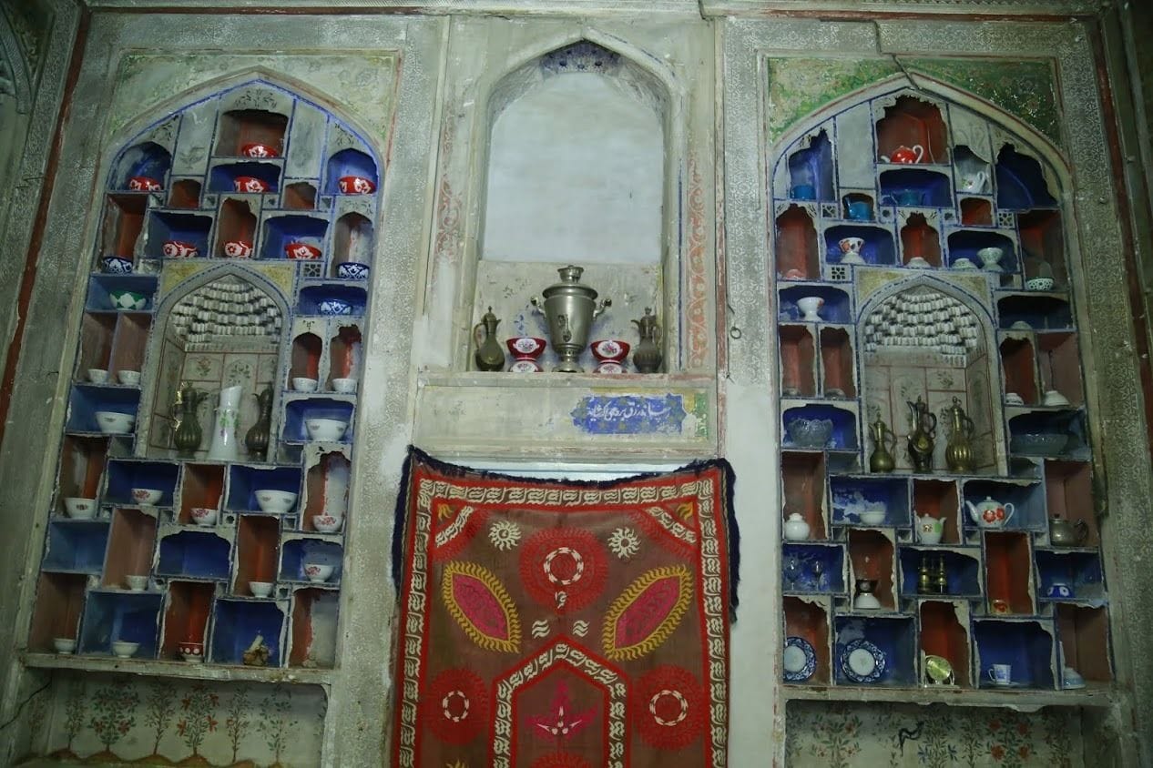 A room with a decorative wall featuring multiple shelves with various items.