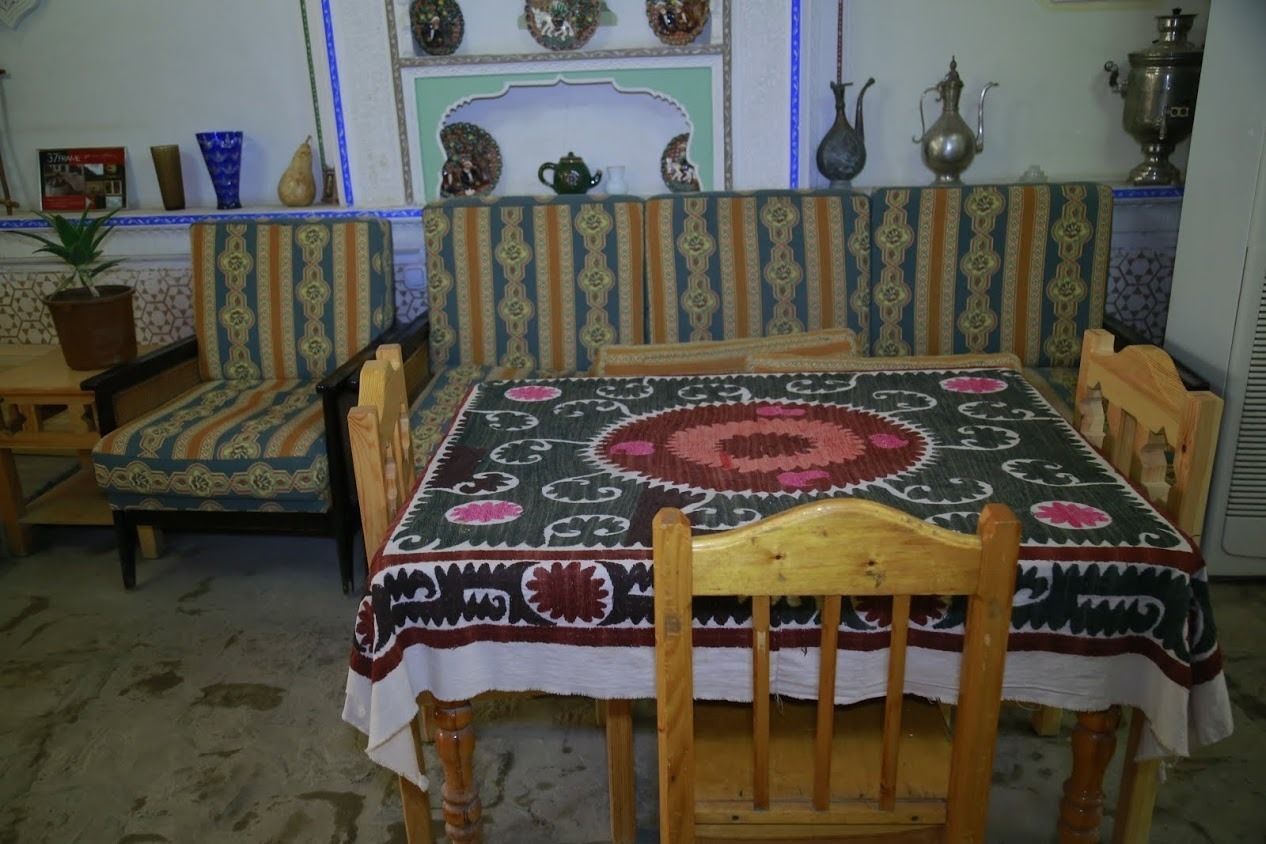 A traditional room with a sofa set, a wooden table, and a patterned tablecloth.