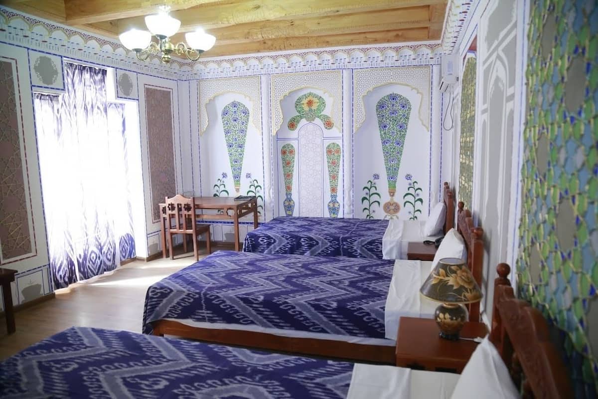 Una habitación con dos camas, una silla de madera, una mesa y un candelabro.