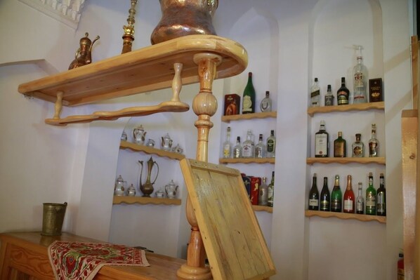 A room with wooden shelves displaying various bottles and a wooden table with a cloth.