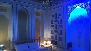 Un dormitorio con cama, mesita de noche, lámpara y paneles decorativos en la pared.