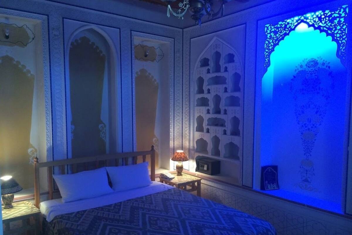 Un dormitorio con cama, mesita de noche, lámpara y paneles decorativos en la pared.