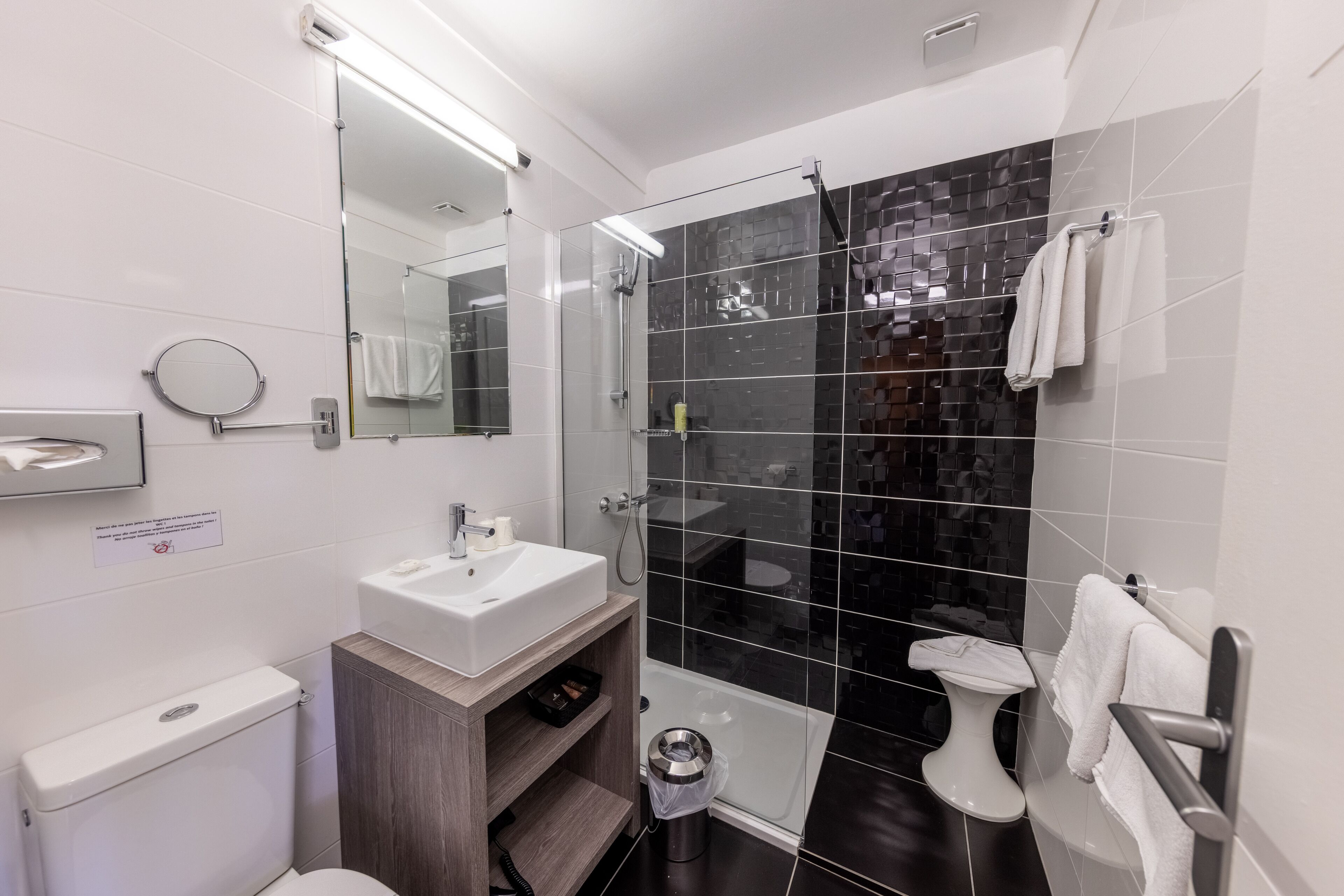 Een moderne badkamer met een glazen douchecabine, een wit wastafelmeubel en een toilet.