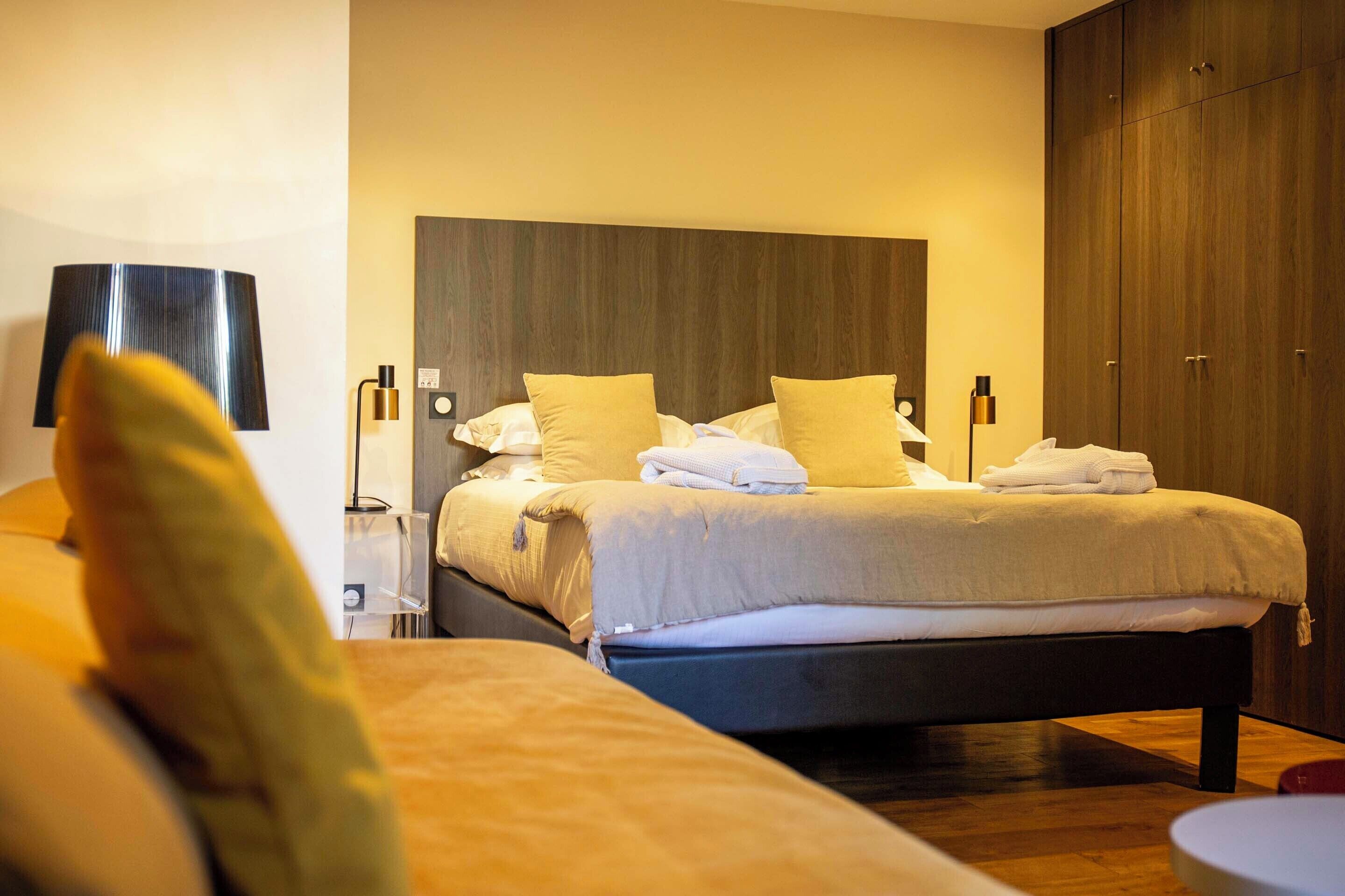 A hotel room with a bed, bedside tables, a lamp, and a wardrobe.