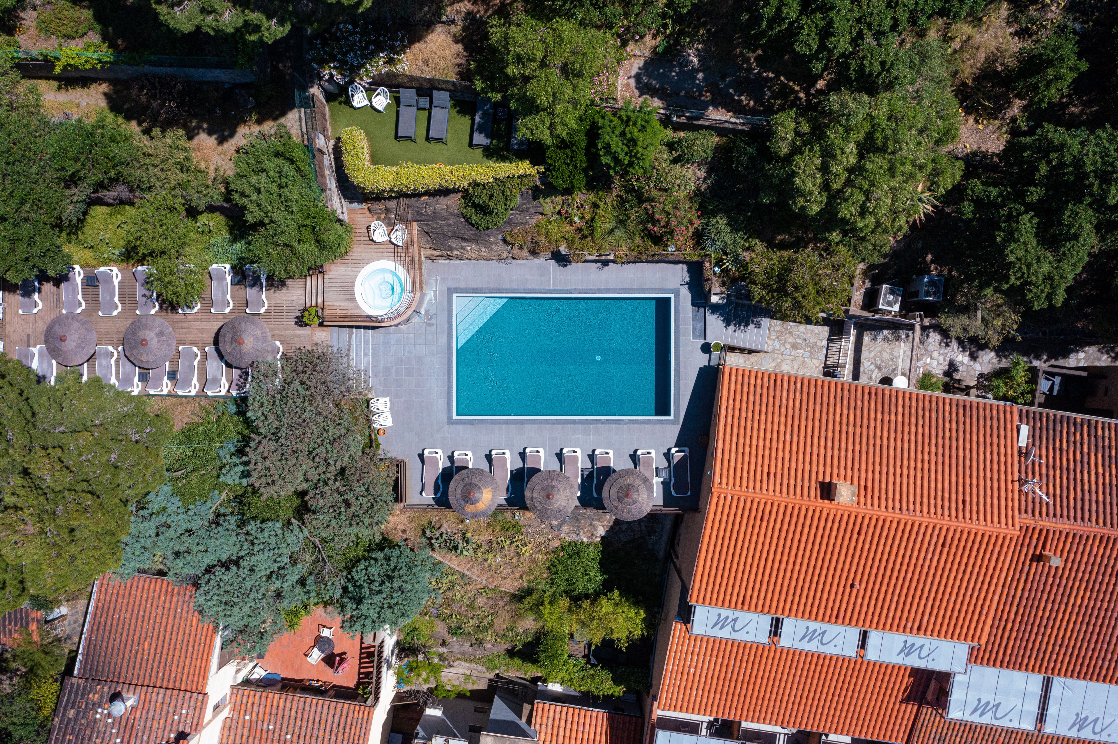 An aerial view of a property with a swimming pool, lounge chairs, and a garden area.