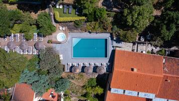 An aerial view of a property with a swimming pool, lounge chairs, and a garden area.