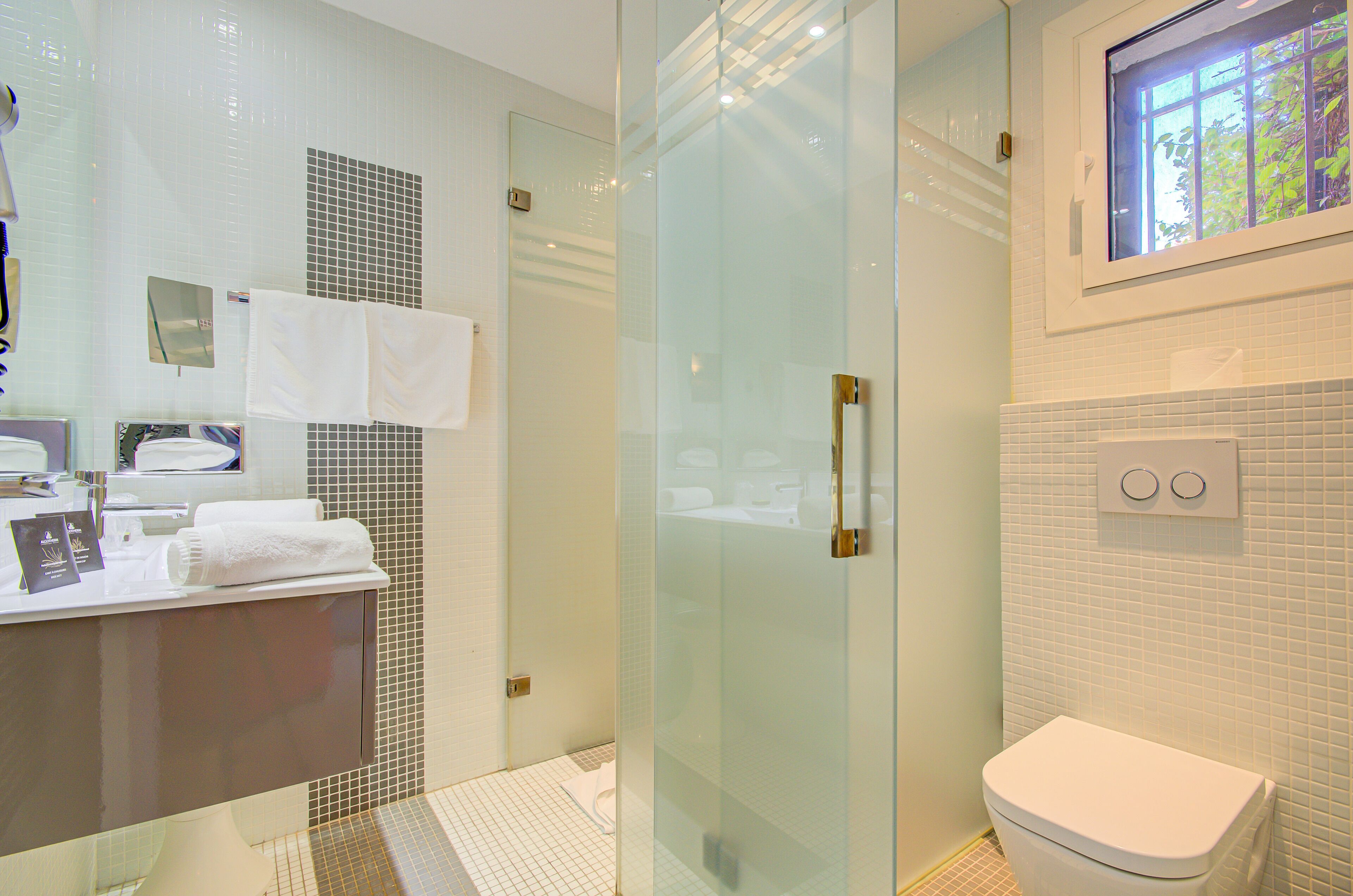 A modern bathroom with a glass shower enclosure, a white toilet, and a sink with a mirror.