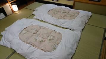 Two tatami mat beds with white bedding and floral-patterned cushions.