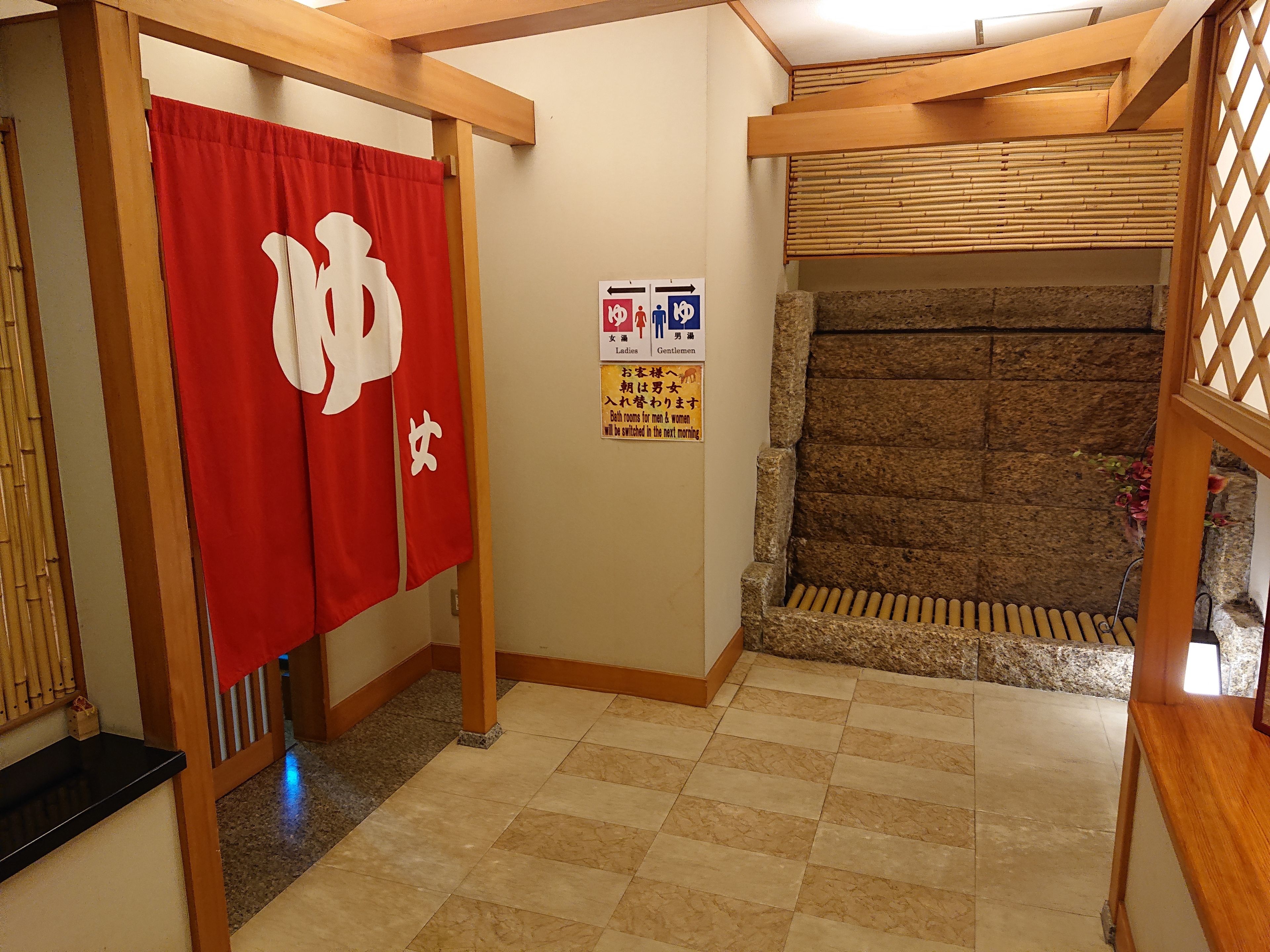 A traditional Japanese room with tatami flooring, a wooden shoji screen, and a red curtain with white characters.