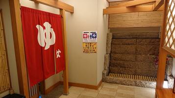 A traditional Japanese room with tatami flooring, a wooden shoji screen, and a red curtain with white characters.