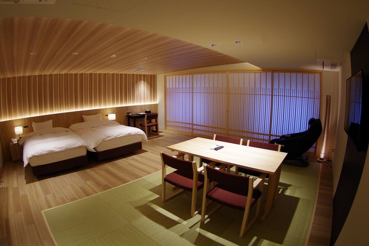 A hotel room with a bed, a desk, a chair, and a massage chair.