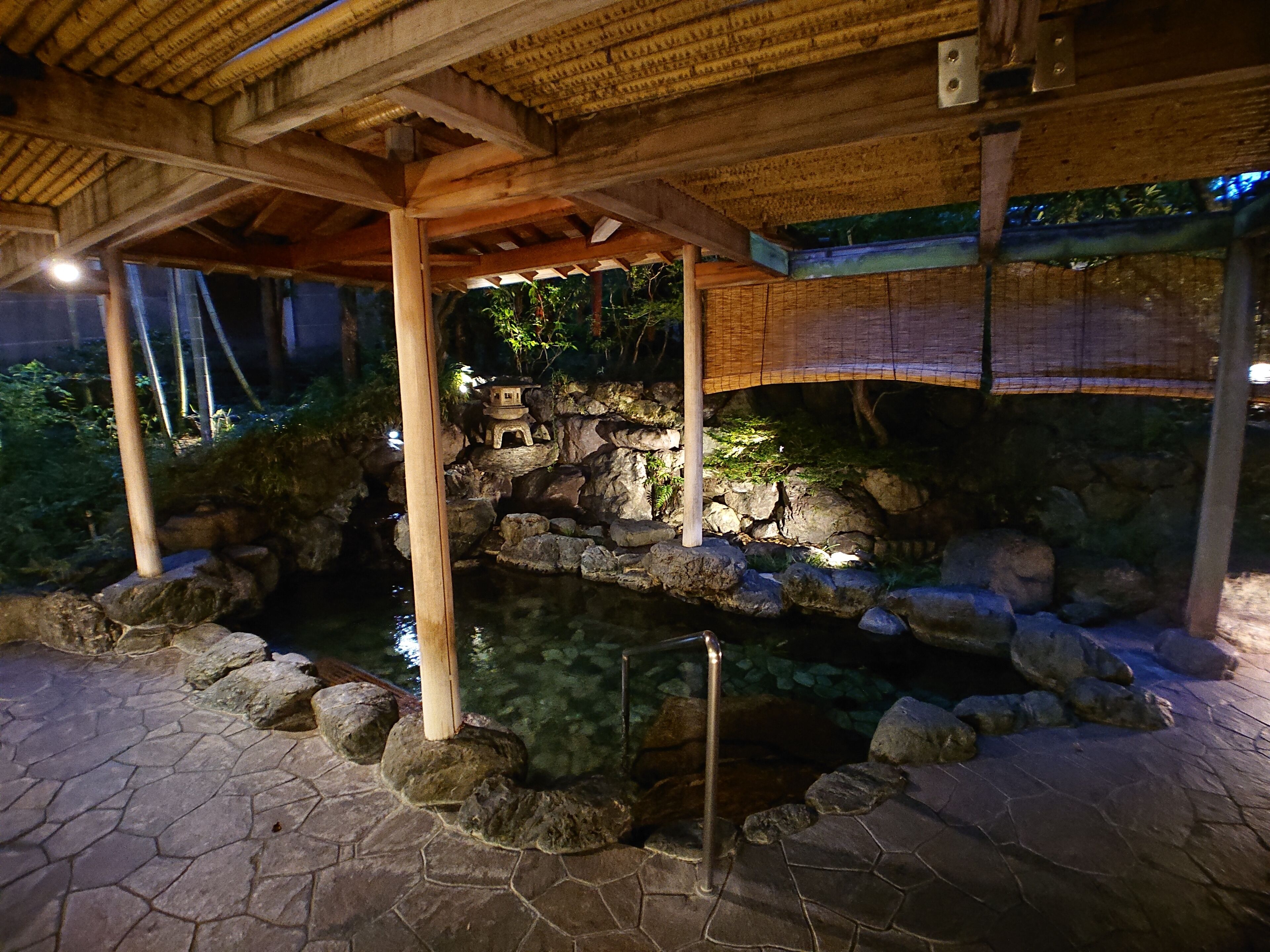 Un estanque de piedra con un puente de madera, rodeado de rocas y plantas.