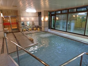 An indoor swimming pool with clear water, wooden steps, and a glass barrier.