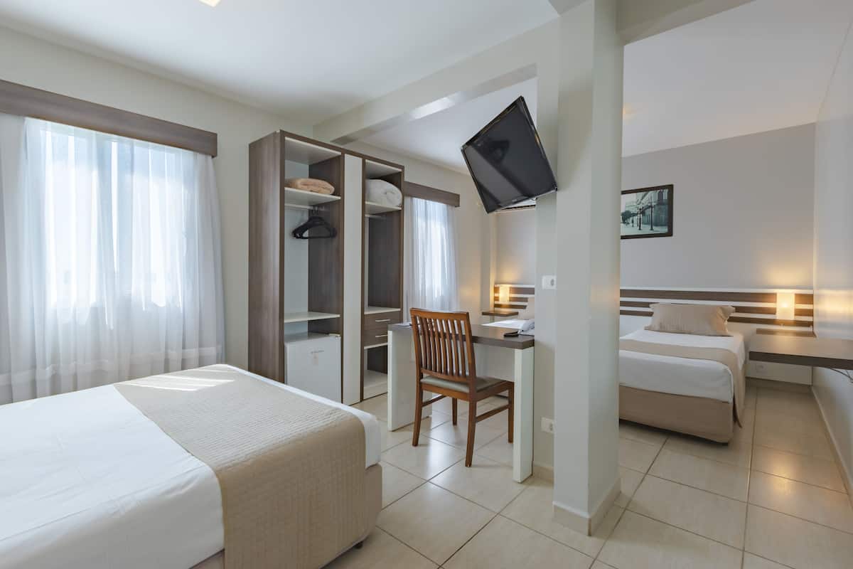 Een hotelkamer met een bed, een bureau, een stoel, een televisie en een kleine zithoek.