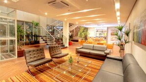 Un intérieur moderne avec un escalier, des canapés en cuir, une table basse en verre et un tapis à rayures.