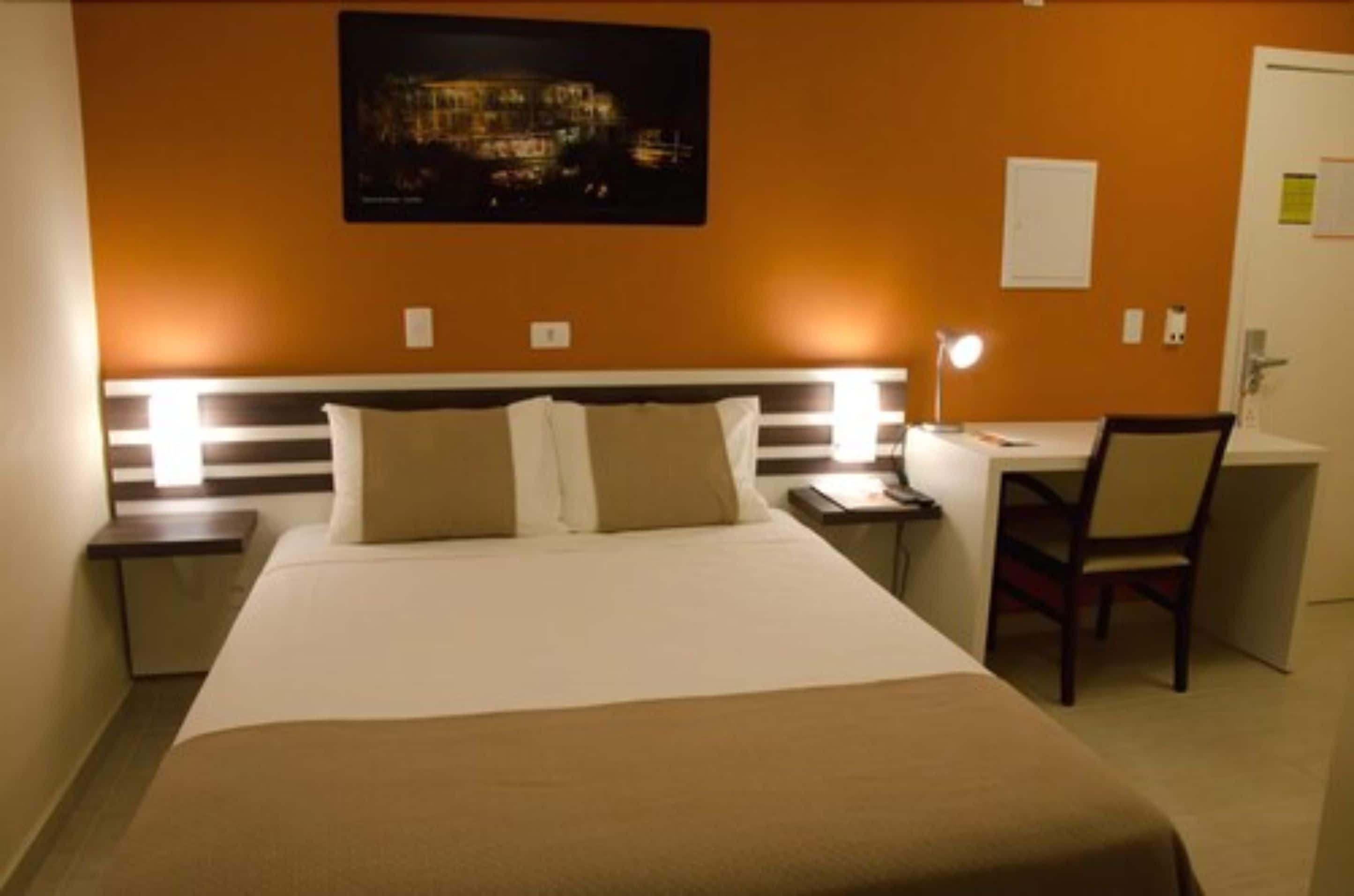 Ein Hotelzimmer mit einem Bett, Nachttischen, einem Schreibtisch und einem Sessel.