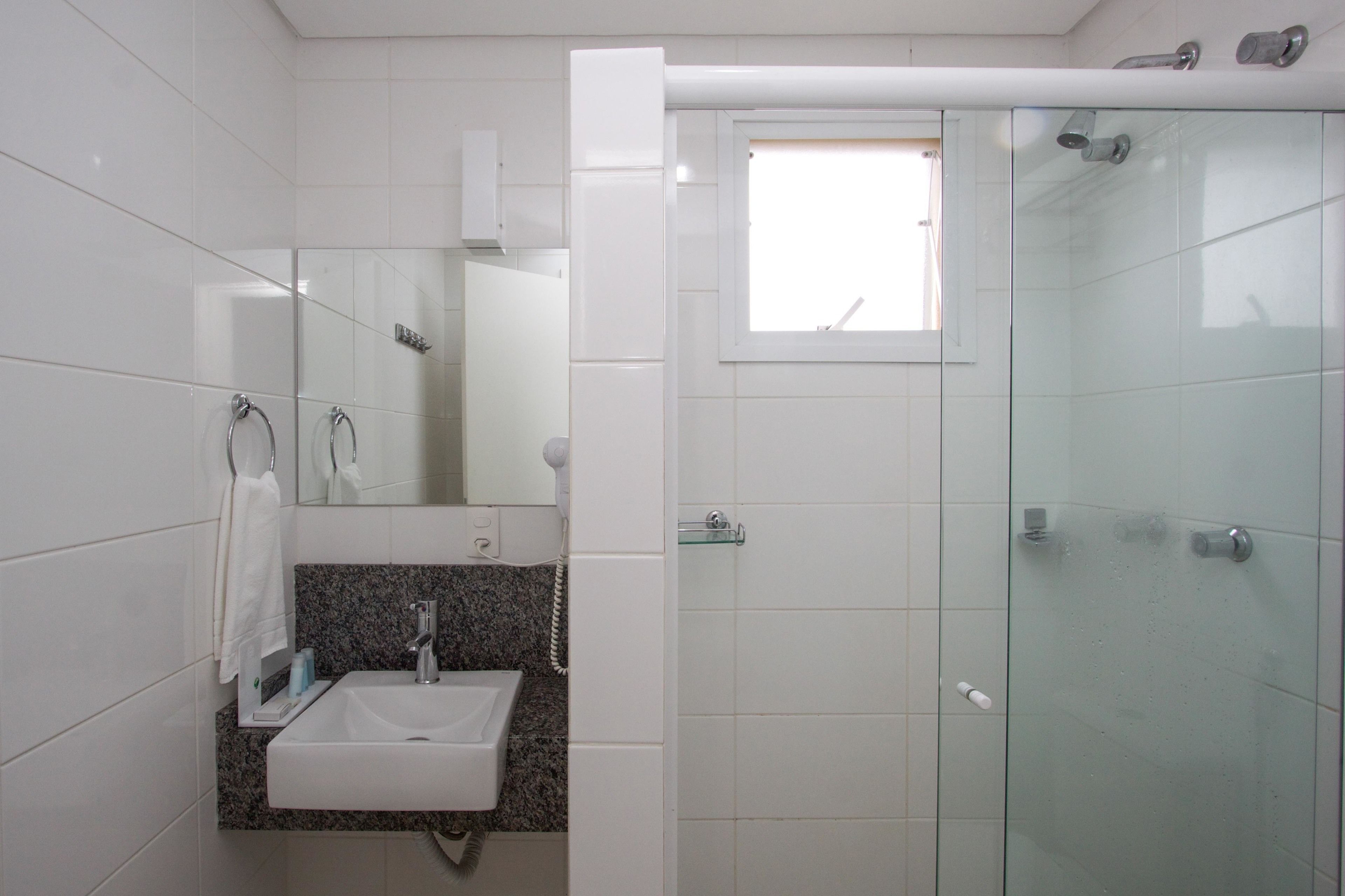 A bathroom with a glass shower enclosure, a sink with a granite countertop, and a mirror above the sink.