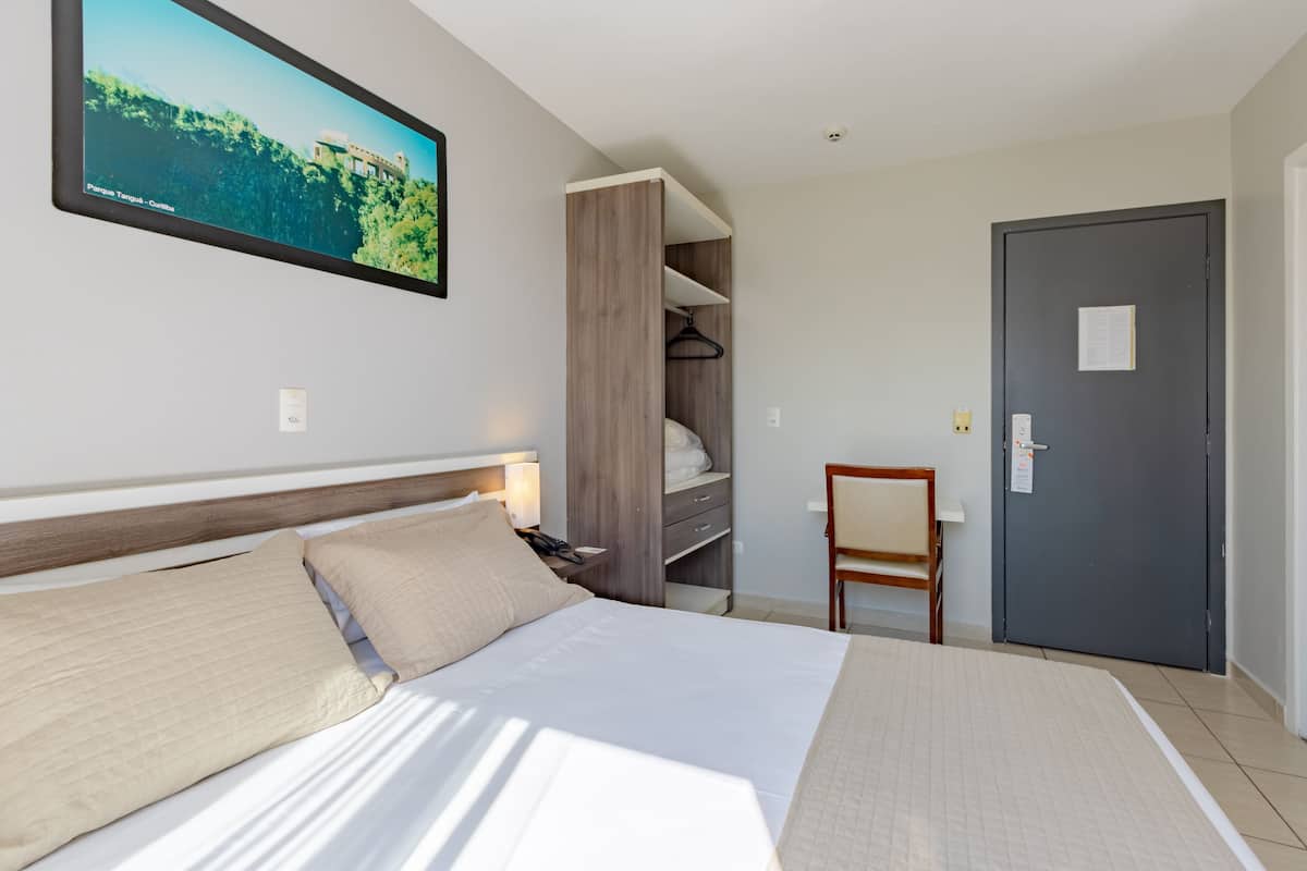 Een hotelkamer met een bed, een kledingkast, een bureau en een deur.