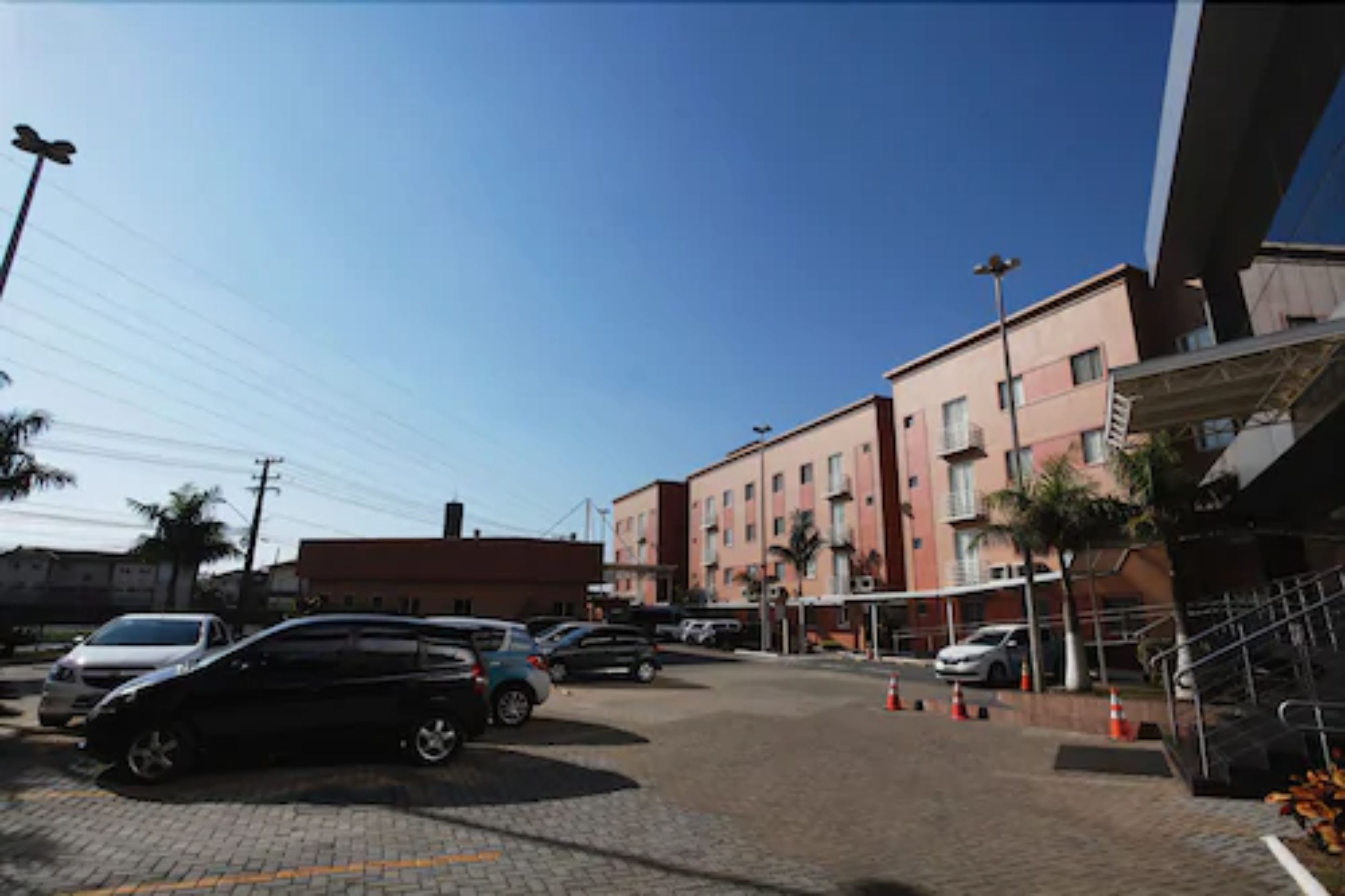 A parking area with multiple cars, a building with a red roof, and a staircase leading to an upper level.