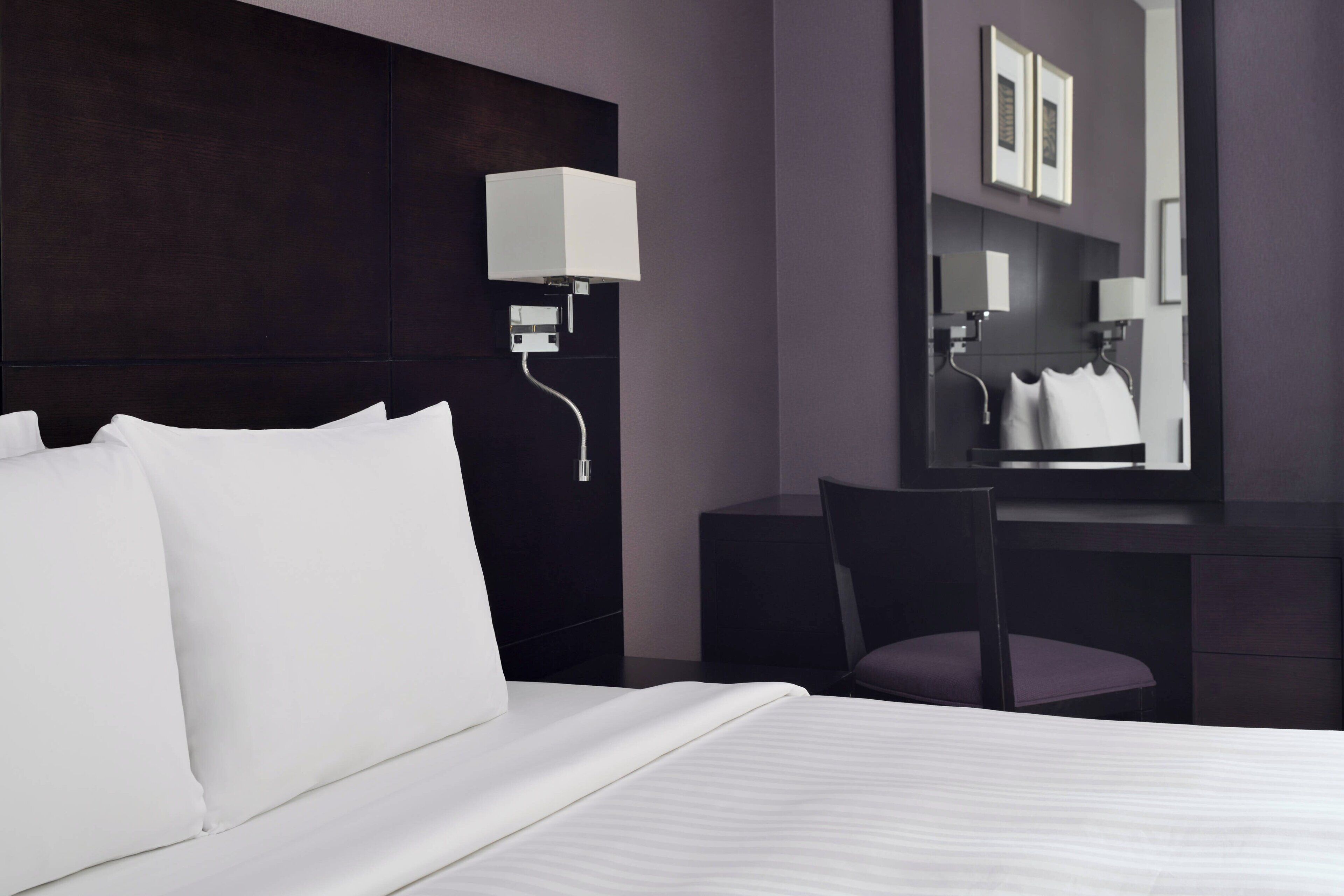 Una habitación de hotel moderna con una cama grande, un escritorio y una silla.