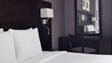 Una habitación de hotel moderna con una cama grande, un escritorio y una silla.