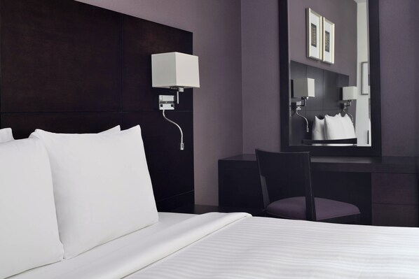 Una habitación de hotel moderna con una cama grande, un escritorio y una silla.