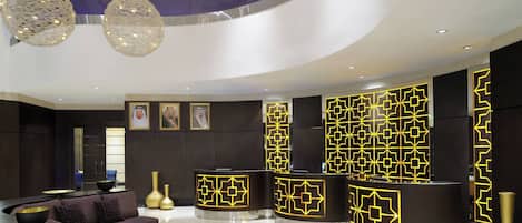 Un vestíbulo moderno con un mostrador de recepción curvo, un sofá e iluminación decorativa.