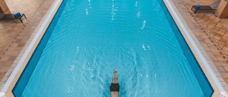 A swimming pool with a person diving at the end.